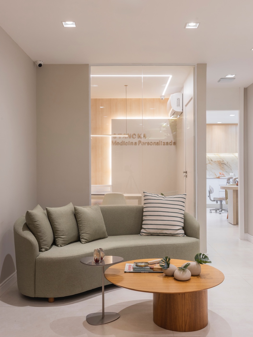 Sala de espera com sofá verde e vista para a recepção